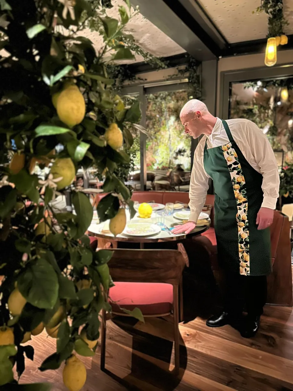 Camerieri in grembiule sartoriale in un ristorante con pergolato di limoni