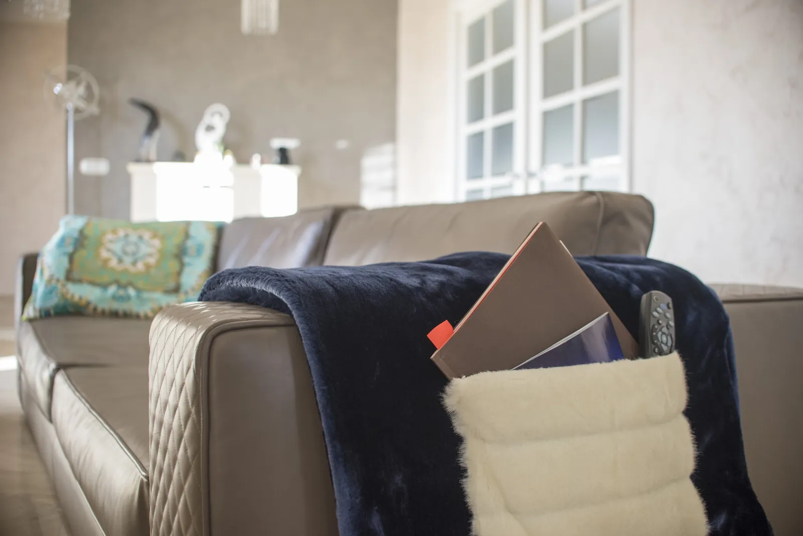 Plaid blu navy con tasca portaoggetti su divano in pelle — Home Design