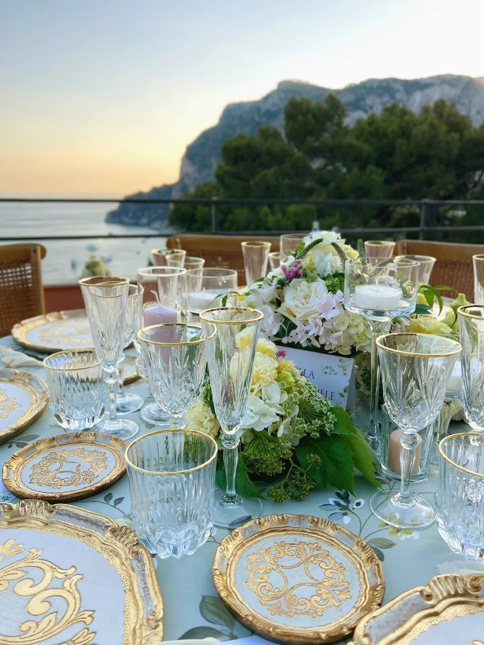 Mise en place wedding al tramonto con piatti dorati e vista mare