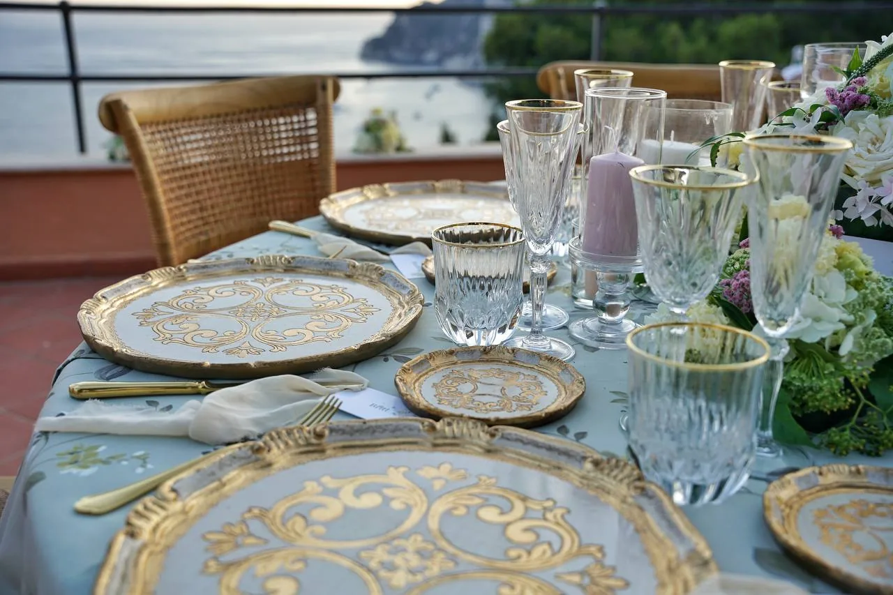 Dettaglio mise en place wedding con vassoi dorati e cristalli, vista mare