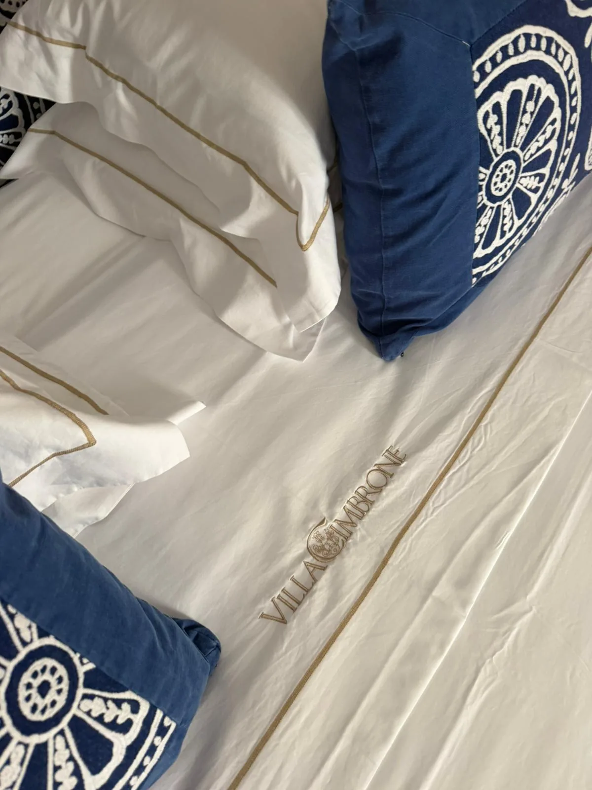 Dettaglio lenzuola in cotone con profilo dorato e monogramma Villa Cimbrone ricamato — Capuano